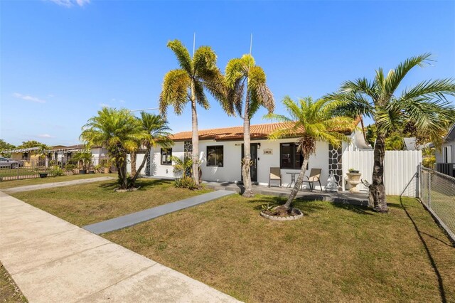 view of front facade with a front lawn, fence, a tile roof, stucco siding, and a gate
