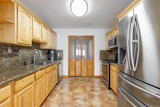 kitchen featuring a sink, dark stone counters, appliances with stainless steel finishes, and light brown cabinetry