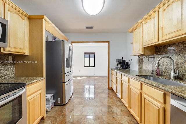 kitchen with visible vents, light brown cabinetry, stone counters, stainless steel appliances, and a sink