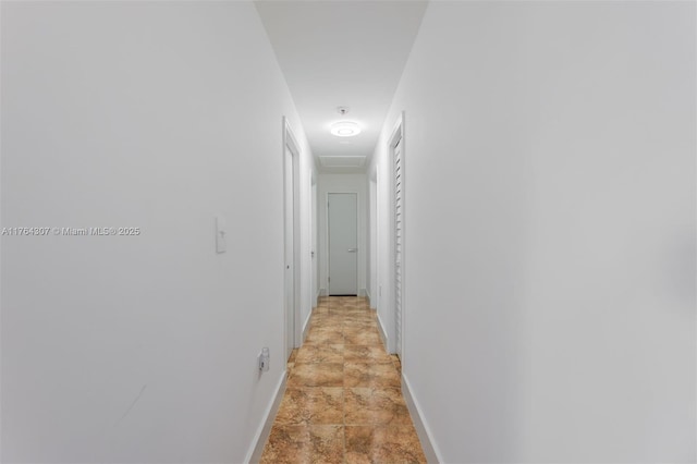 hall featuring stone finish flooring and baseboards