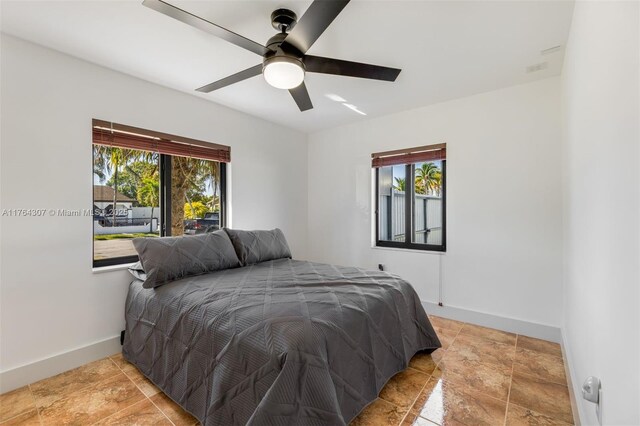 bedroom featuring multiple windows, a ceiling fan, and baseboards