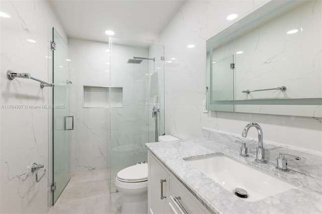 full bathroom with a marble finish shower, toilet, and vanity