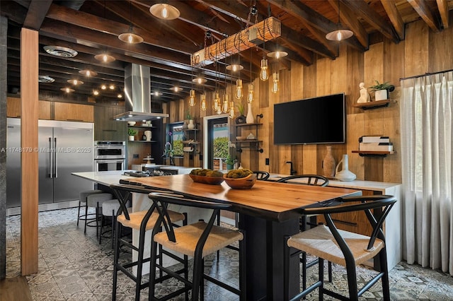 interior space with wooden walls, beam ceiling, island exhaust hood, stainless steel appliances, and open shelves