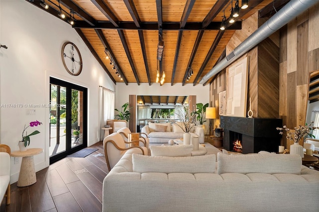 living area with track lighting, beamed ceiling, and wood ceiling