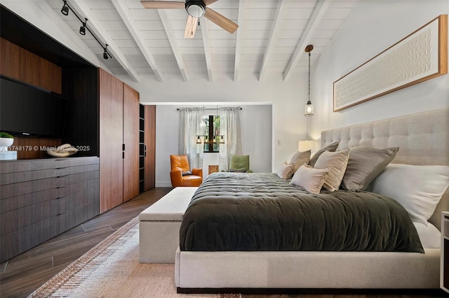 bedroom featuring beamed ceiling, rail lighting, ceiling fan, and wood finished floors