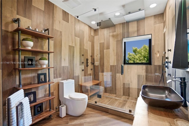 full bath with visible vents, toilet, tiled shower, tile walls, and a sink