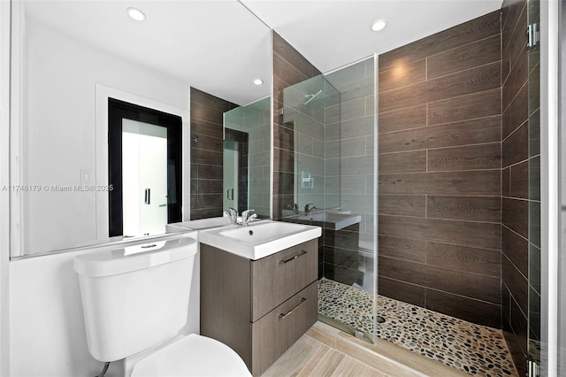 bathroom with recessed lighting, toilet, vanity, and a tile shower