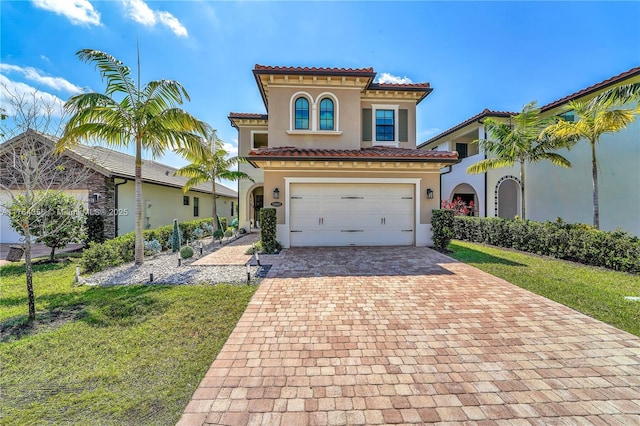 mediterranean / spanish house featuring stucco siding, a front lawn, decorative driveway, an attached garage, and a tiled roof