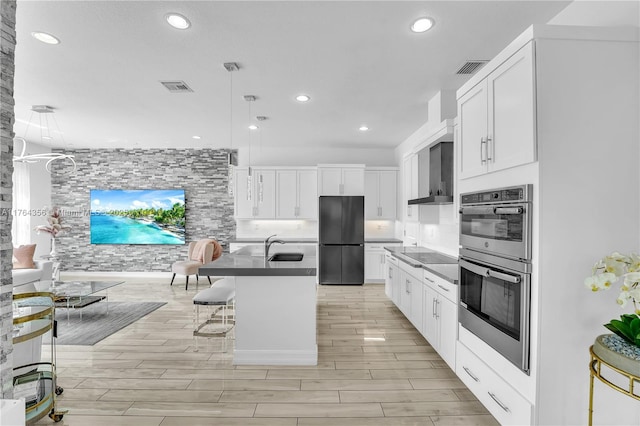 kitchen featuring visible vents, a sink, black appliances, white cabinetry, and wall chimney range hood