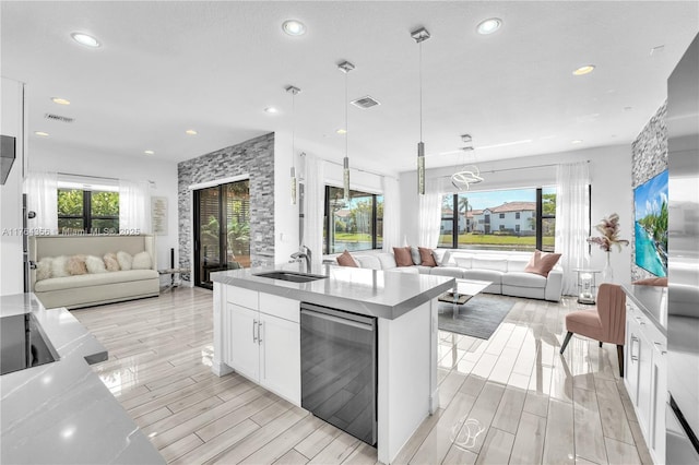 kitchen with wood tiled floor, visible vents, open floor plan, and a sink