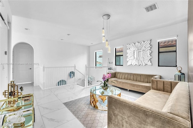 living area featuring arched walkways, visible vents, and marble finish floor