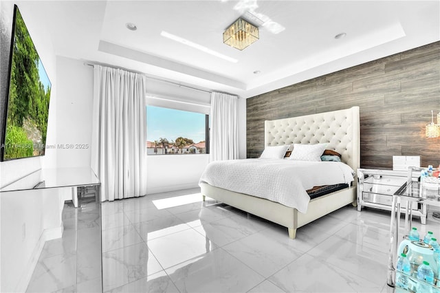 bedroom featuring marble finish floor, baseboards, an accent wall, and a tray ceiling