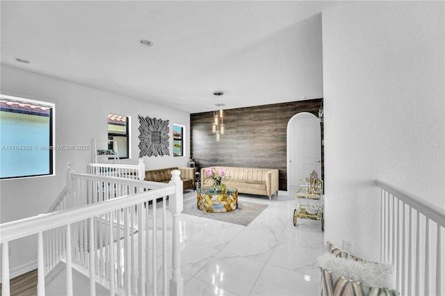 bedroom with an accent wall, recessed lighting, marble finish floor, and wood walls