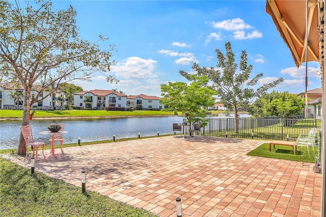 view of patio / terrace with fence, a water view, and a residential view