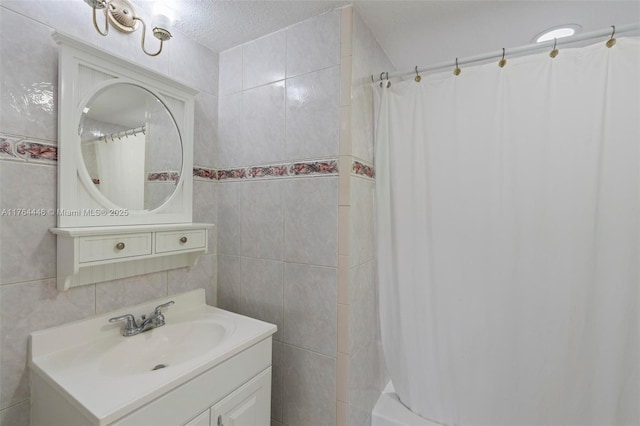 full bath with vanity, tile walls, and a textured ceiling