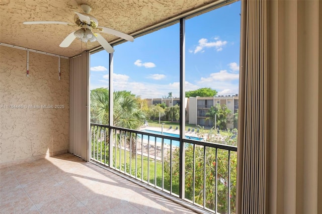 unfurnished sunroom with ceiling fan