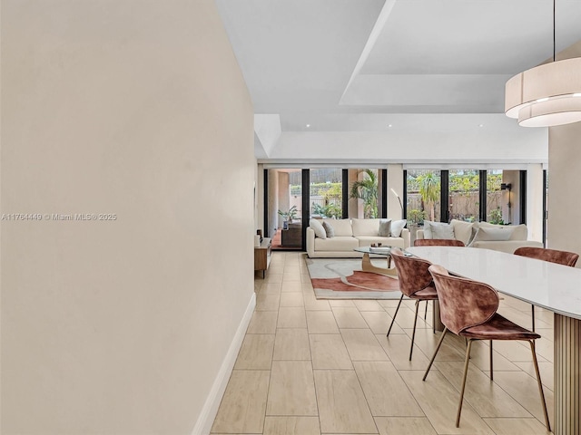 living room with plenty of natural light, a tray ceiling, and baseboards