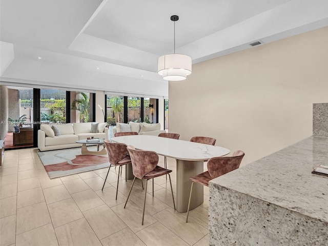 dining room featuring a wealth of natural light, visible vents, a tray ceiling, and light tile patterned floors