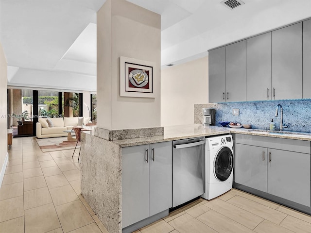 kitchen featuring visible vents, gray cabinetry, a sink, washer / dryer, and dishwasher