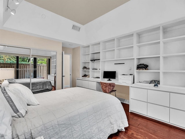 bedroom featuring visible vents, built in study area, dark wood-type flooring, and access to outside