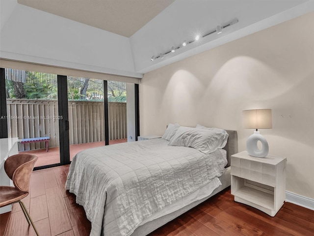 bedroom featuring access to exterior, rail lighting, wood finished floors, and baseboards