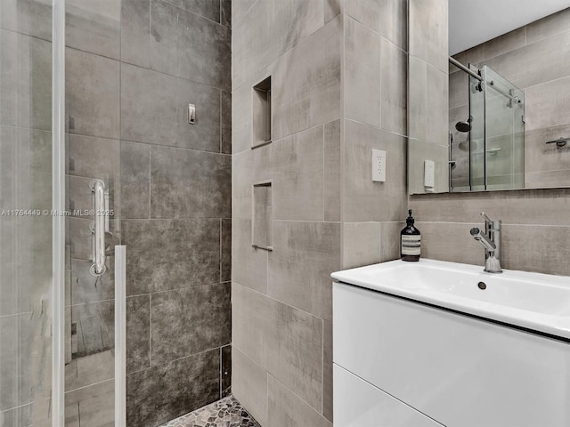 bathroom with tasteful backsplash, vanity, tile walls, and a shower stall