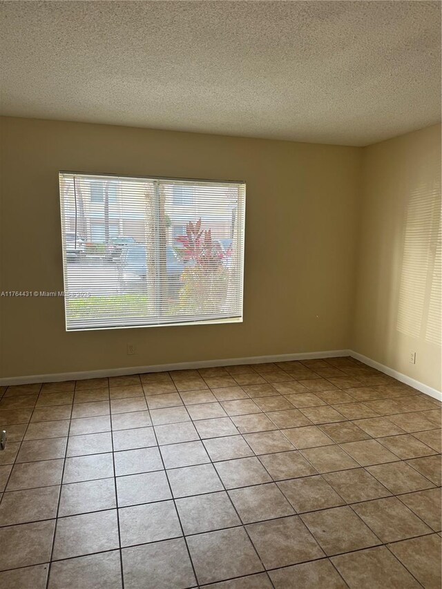 815 W Boynton Beach Blvd Unit 6-103, Boynton Beach, FL 33426 - spare room featuring a textured ceiling and tile patterned flooring