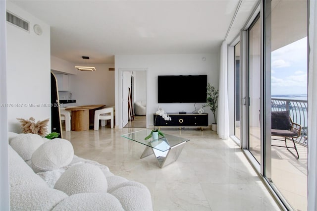 living room with floor to ceiling windows, visible vents, and marble finish floor