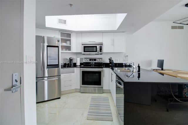 kitchen featuring visible vents, a peninsula, stainless steel appliances, and a sink