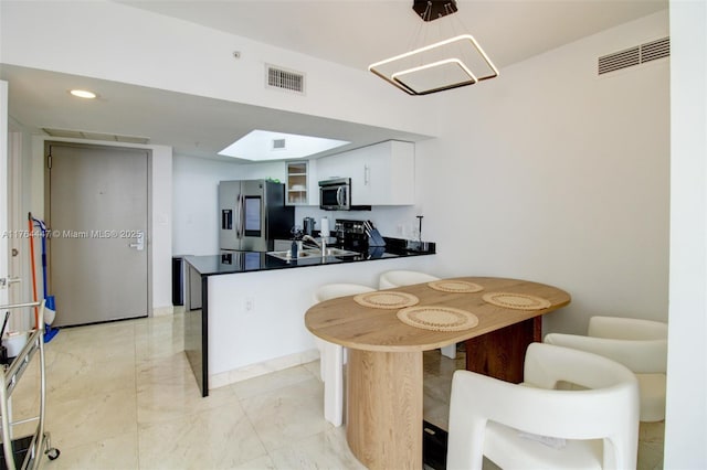 kitchen with stainless steel appliances, visible vents, a peninsula, and white cabinets