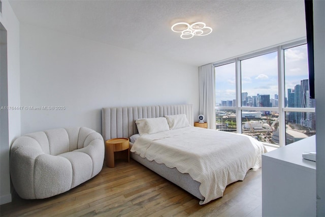 bedroom featuring a city view, radiator, light wood-style floors, and expansive windows