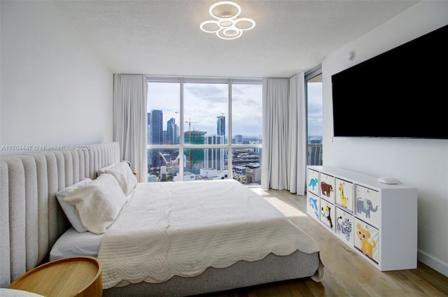 bedroom with a wall of windows, light wood-style floors, and baseboards