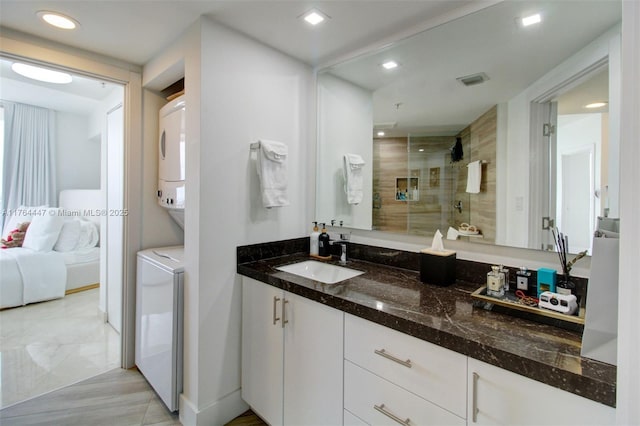 ensuite bathroom featuring stacked washer / dryer, a shower stall, recessed lighting, ensuite bathroom, and vanity