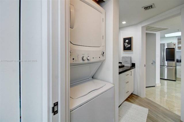 laundry area with visible vents, light wood-type flooring, laundry area, recessed lighting, and stacked washing maching and dryer