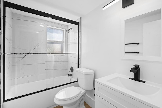 full bath with vanity, toilet, and shower / bath combination with glass door