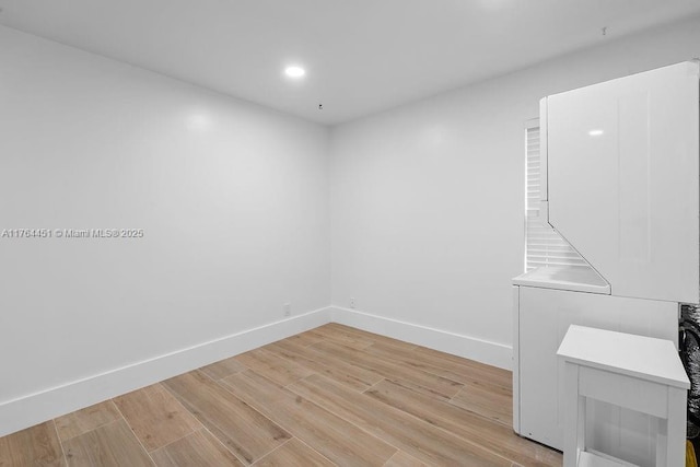 empty room featuring recessed lighting, baseboards, and light wood finished floors