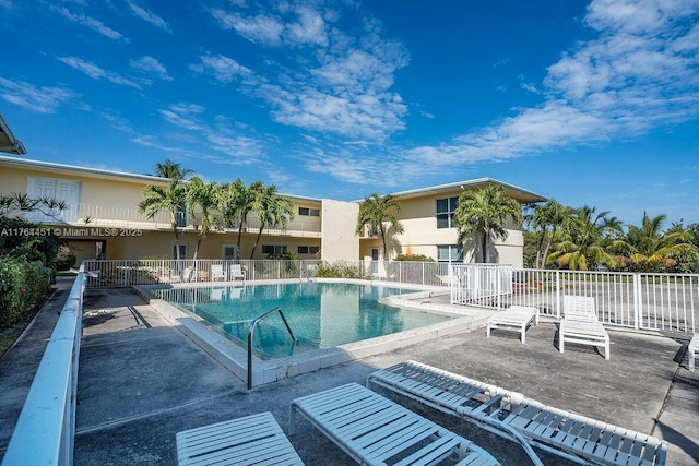 community pool with a patio and fence