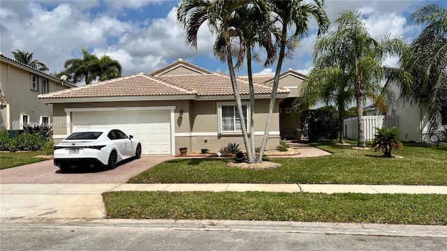 ranch-style house with stucco siding, a tile roof, decorative driveway, a front yard, and a garage