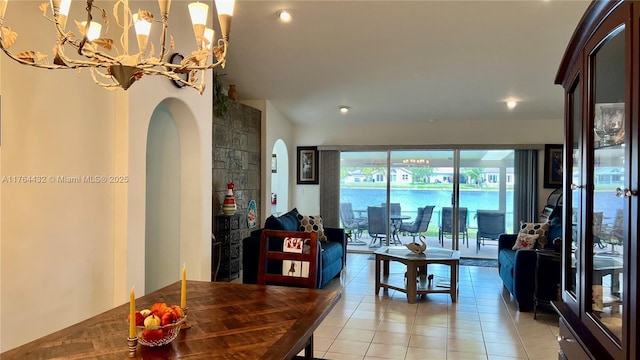 living area with a chandelier, light tile patterned floors, arched walkways, and a water view