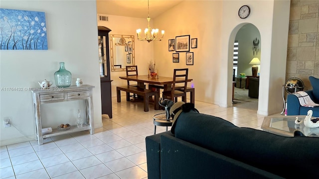 living area featuring light tile patterned floors, visible vents, arched walkways, and an inviting chandelier