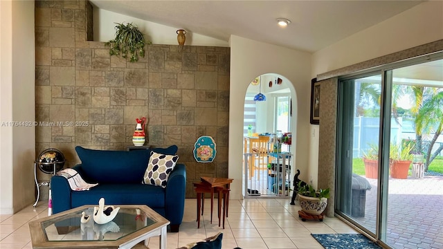 living area with light tile patterned floors, arched walkways, and vaulted ceiling