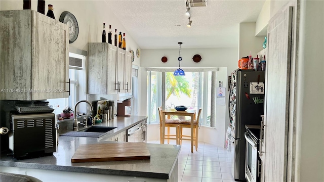 kitchen with a sink, decorative light fixtures, a textured ceiling, stainless steel appliances, and light tile patterned flooring