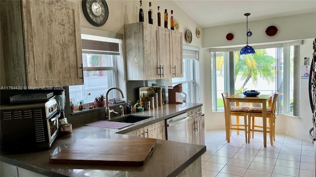 kitchen with dark countertops, pendant lighting, stainless steel dishwasher, light tile patterned flooring, and a sink