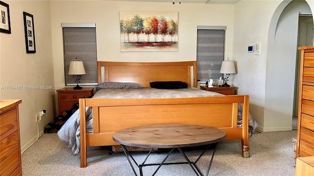 carpeted bedroom featuring baseboards and arched walkways