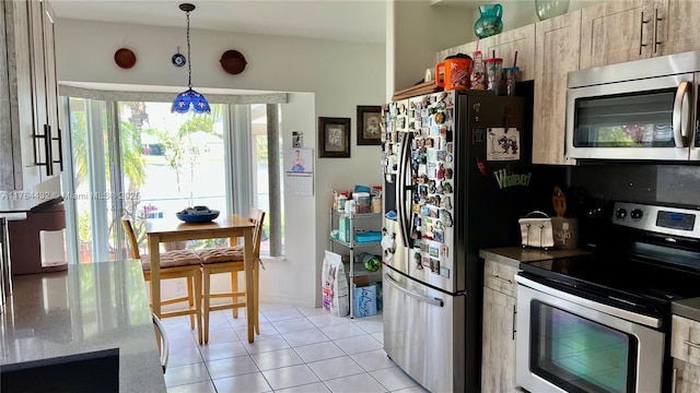 kitchen with hanging light fixtures, light stone counters, light tile patterned flooring, and stainless steel appliances