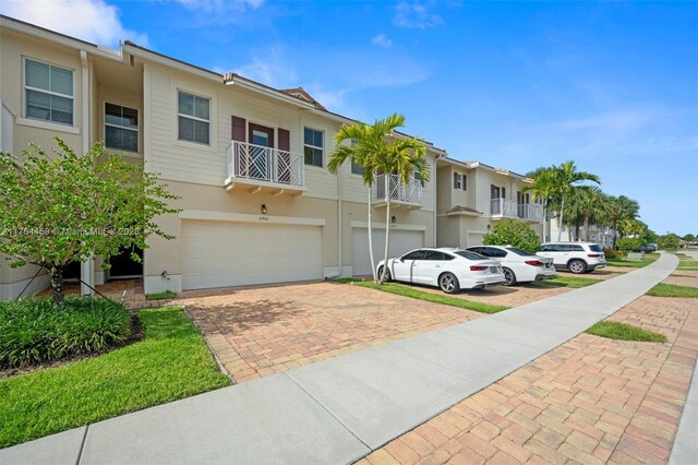 11941 Park Central Unit 11941, Royal Palm Beach, FL 33411 - view of property featuring an attached garage, decorative driveway, stucco siding, and a residential view