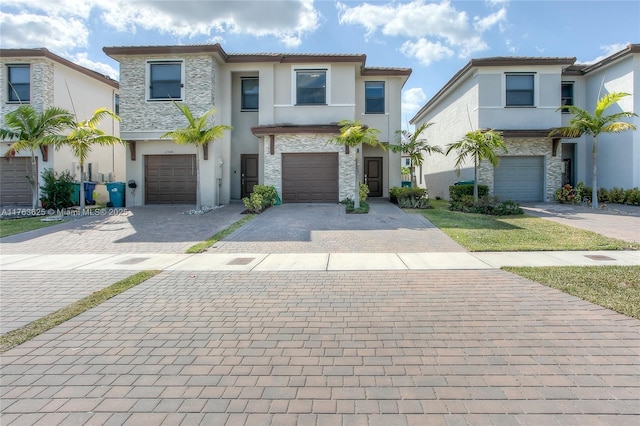 view of front of property featuring an attached garage, stucco siding, stone siding, a tiled roof, and decorative driveway