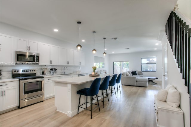 kitchen with a sink, backsplash, open floor plan, a center island, and appliances with stainless steel finishes