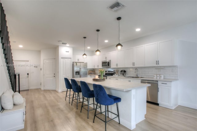 kitchen with a kitchen bar, visible vents, a sink, stainless steel appliances, and light countertops