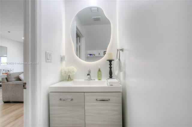 bathroom with visible vents, vanity, and wood finished floors